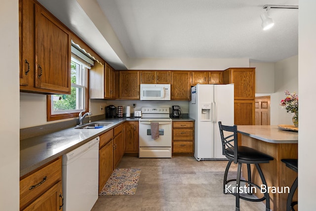 kitchen with white appliances, a sink, and brown cabinetry