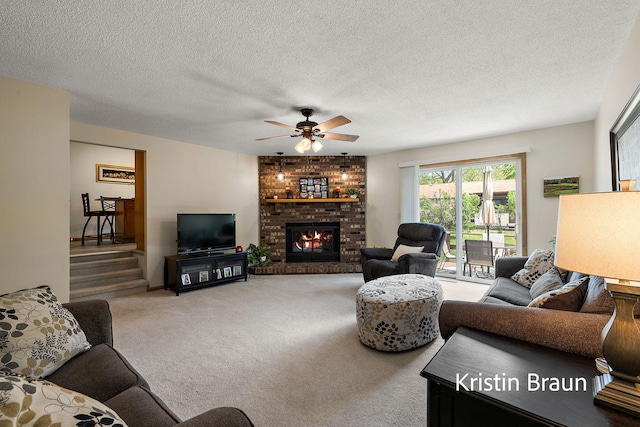 living area featuring ceiling fan, carpet floors, a fireplace, and a textured ceiling