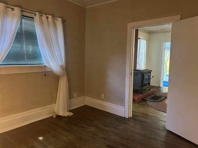 1902 W Ogilvie Ave, Baldwin, MI 49304 - unfurnished room featuring a wood stove, dark wood-type flooring, ornamental molding, and baseboards