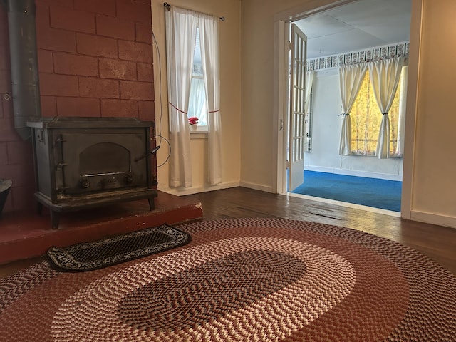 1902 W Ogilvie Ave, Baldwin, MI 49304 - unfurnished room featuring a wood stove, wood finished floors, and baseboards
