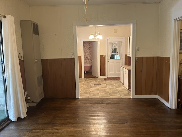 1902 W Ogilvie Ave, Baldwin, MI 49304 - unfurnished dining area featuring a heating unit, a chandelier, light wood finished floors, a wainscoted wall, and wood walls