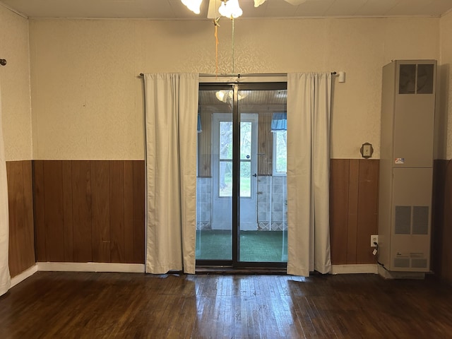 1902 W Ogilvie Ave, Baldwin, MI 49304 - empty room with a heating unit, wood finished floors, a textured wall, a wainscoted wall, and wooden walls