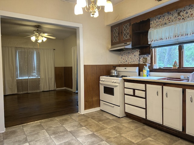 1902 W Ogilvie Ave, Baldwin, MI 49304 - kitchen featuring white gas range oven, a chandelier, wainscoting, under cabinet range hood, and wood walls