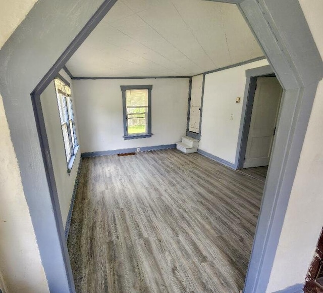 unfurnished living room featuring wood finished floors, baseboards, and ornamental molding