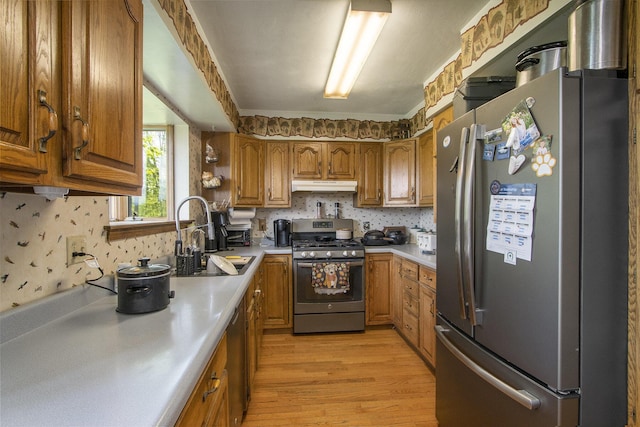 6528 Douglas Ave, Kalamazoo, MI 49009 - kitchen with appliances with stainless steel finishes, under cabinet range hood, a sink, light countertops, and brown cabinetry