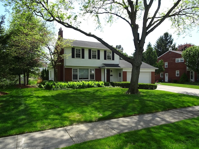 view of front of home featuring concrete driveway, a chimney, an attached garage, brick siding, and a front yard