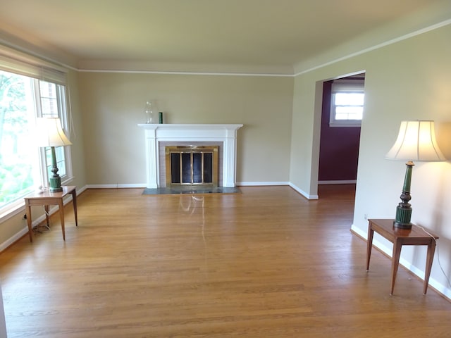 unfurnished living room with wood finished floors, baseboards, crown molding, and a fireplace with flush hearth