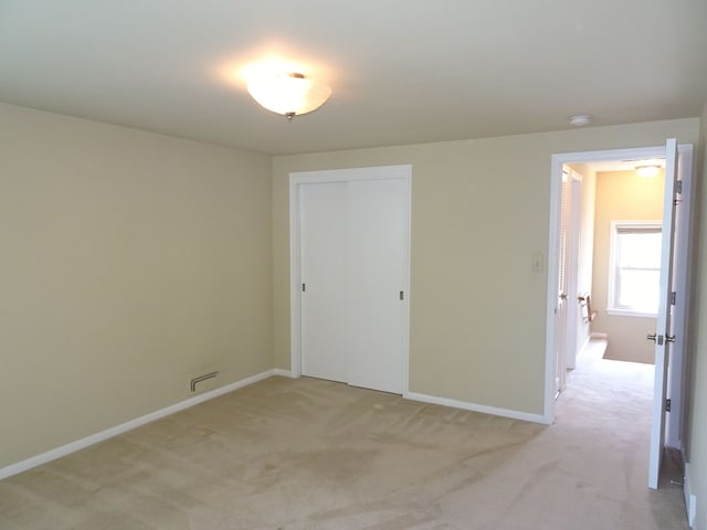 spare room with light colored carpet, baseboards, and a smoke detector