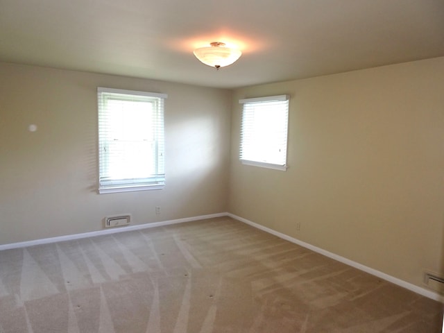 spare room featuring baseboards and light carpet