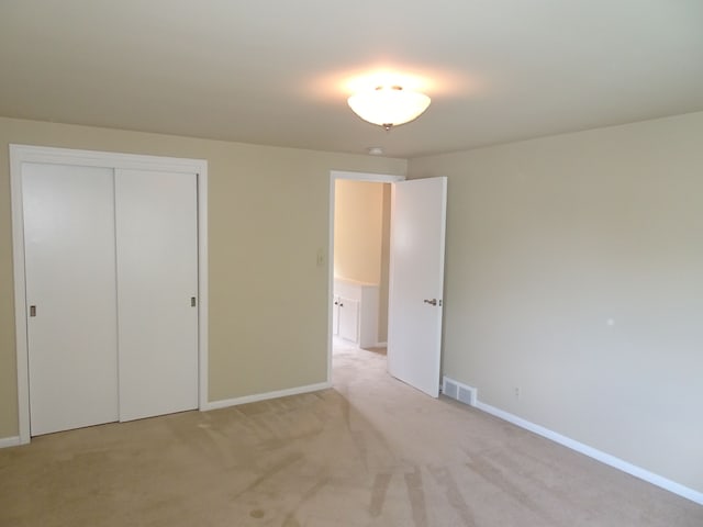 unfurnished bedroom featuring baseboards, light colored carpet, and a closet