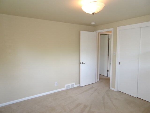 unfurnished bedroom featuring light colored carpet, a closet, and baseboards