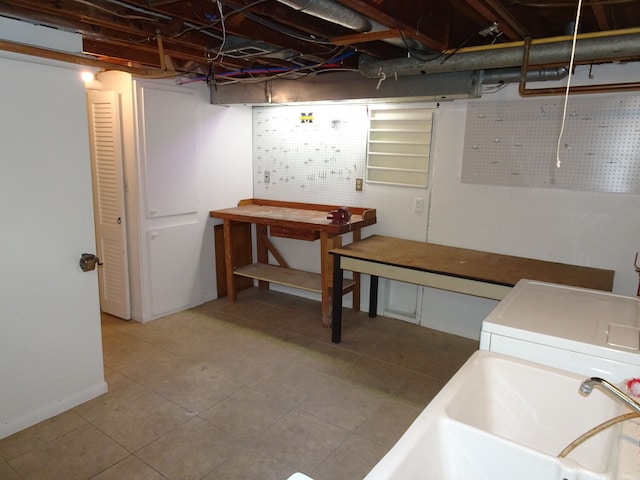 unfinished basement with a workshop area, a sink, tile patterned floors, and washer / dryer