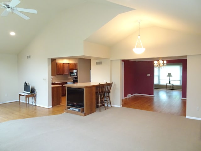 kitchen featuring appliances with stainless steel finishes, high vaulted ceiling, brown cabinets, light countertops, and ceiling fan