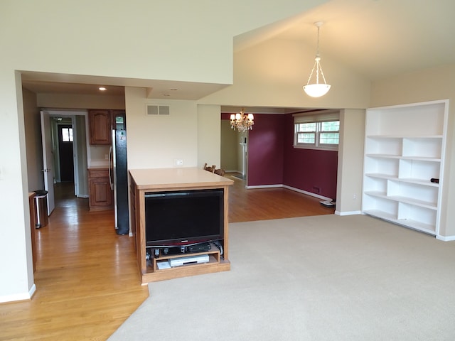 kitchen with freestanding refrigerator, built in features, light countertops, a chandelier, and open floor plan