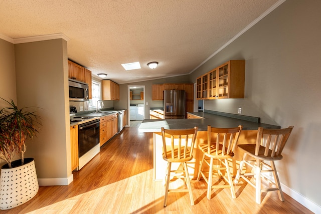 2330 N Rath Rd, Ludington, MI 49431 - kitchen with appliances with stainless steel finishes, washer and dryer, crown molding, light wood finished floors, and a peninsula