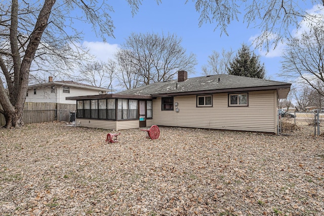 1772 Lombard St, Benton Harbor, MI 49022 - rear view of house with a sunroom, a chimney, a fenced backyard, a gate, and a shingled roof