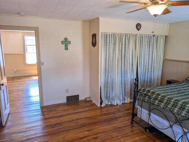 120 N Main St, Scottville, MI 49454 - bedroom featuring wood-type flooring, wainscoting, wooden walls, and ceiling fan