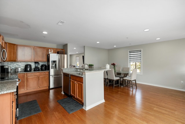 50107 Harding St, Canton, MI 48188 - kitchen featuring stainless steel appliances, wood finished floors, a kitchen island with sink, recessed lighting, and light stone countertops
