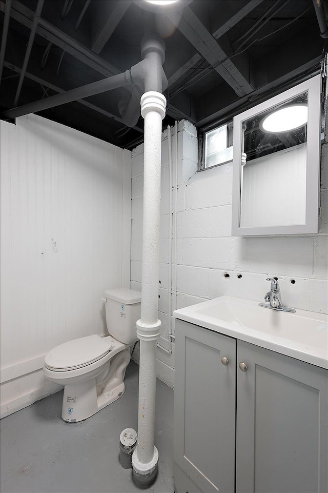 half bath featuring finished concrete flooring, toilet, and vanity