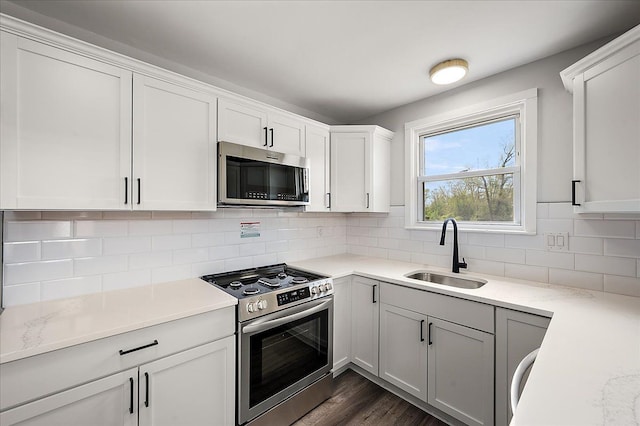 kitchen featuring stainless steel appliances, a sink, white cabinets, and tasteful backsplash