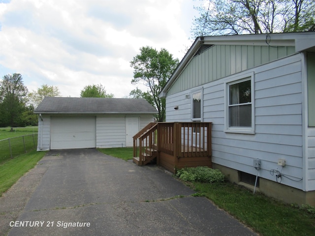 view of front of property with an outdoor structure, board and batten siding, a detached garage, fence, and driveway