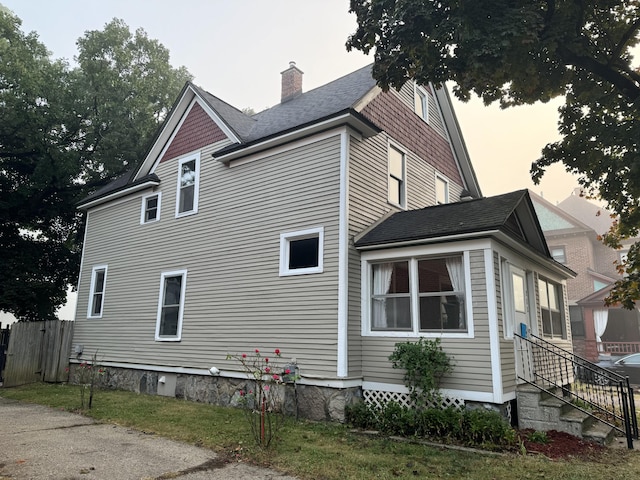 212 Rose Pl, Kalamazoo, MI 49001 - view of side of home with a chimney, fence, and roof with shingles