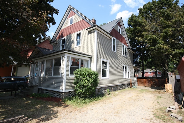 212 Rose Pl, Kalamazoo, MI 49001 - view of home's exterior with a chimney, fence, and roof with shingles