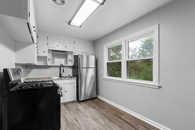 854 Hinckley Blvd, Jackson, MI 49203 - kitchen featuring gas range oven, freestanding refrigerator, a sink, decorative backsplash, and white cabinetry