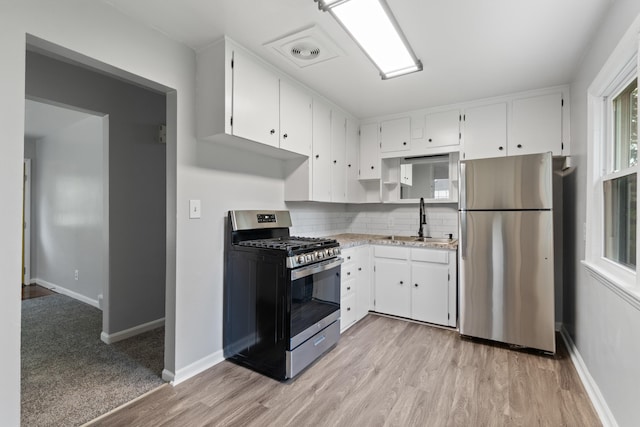 854 Hinckley Blvd, Jackson, MI 49203 - kitchen with appliances with stainless steel finishes, a sink, white cabinetry, decorative backsplash, and light wood-style floors
