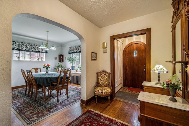 1602 Linwood Ave, Flint, MI 48503 - entrance foyer with arched walkways, dark wood-style floors, a textured wall, a textured ceiling, and a baseboard heating unit