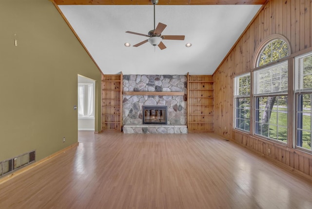 11317 N Dr, Brooklyn, MI 49230 - unfurnished living room featuring light wood-style floors, plenty of natural light, ceiling fan, wooden walls, and a fireplace