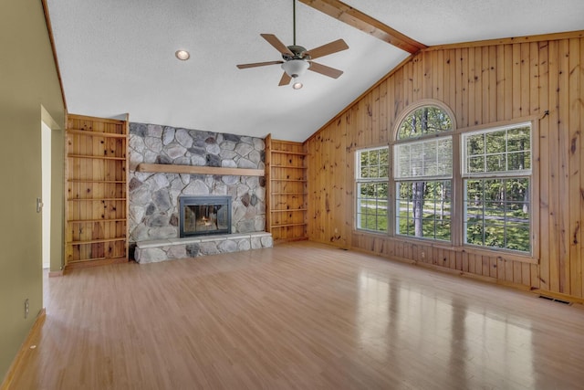 11317 N Dr, Brooklyn, MI 49230 - unfurnished living room with wood finished floors, wooden walls, a fireplace, a ceiling fan, and baseboards