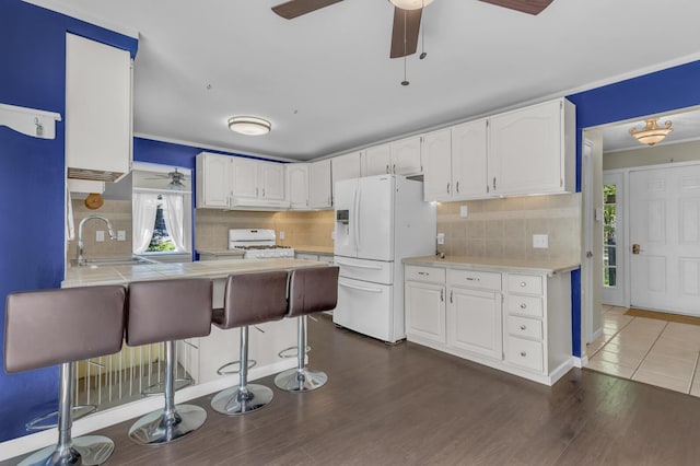 11317 N Dr, Brooklyn, MI 49230 - kitchen with white appliances, a peninsula, a sink, white cabinets, and a breakfast bar