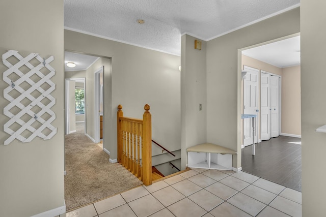 11317 N Dr, Brooklyn, MI 49230 - hallway with an upstairs landing, crown molding, baseboards, a textured ceiling, and tile patterned flooring