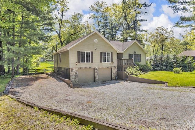 11317 N Dr, Brooklyn, MI 49230 - view of front of home featuring gravel driveway, stone siding, a garage, and fence
