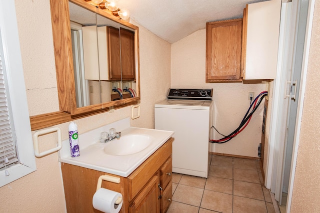 bathroom featuring washer / dryer, vanity, tile patterned flooring, and vaulted ceiling