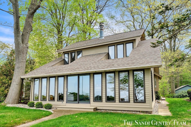 back of house featuring a shingled roof and a yard