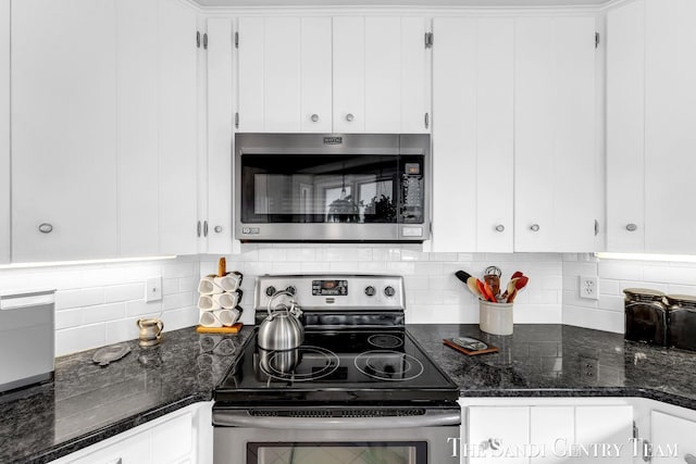 kitchen featuring stainless steel appliances, white cabinets, tasteful backsplash, and dark stone countertops