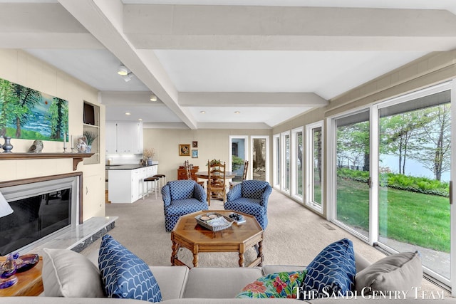 carpeted living area with beam ceiling and a glass covered fireplace