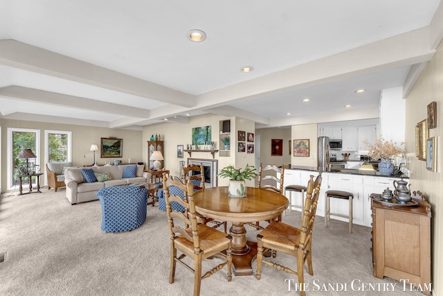 dining area featuring light carpet, recessed lighting, beam ceiling, and a fireplace