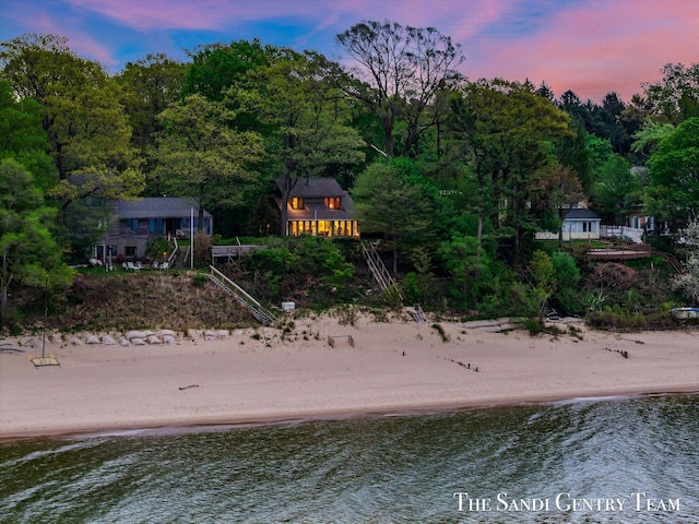 water view featuring nearby beach and a forest