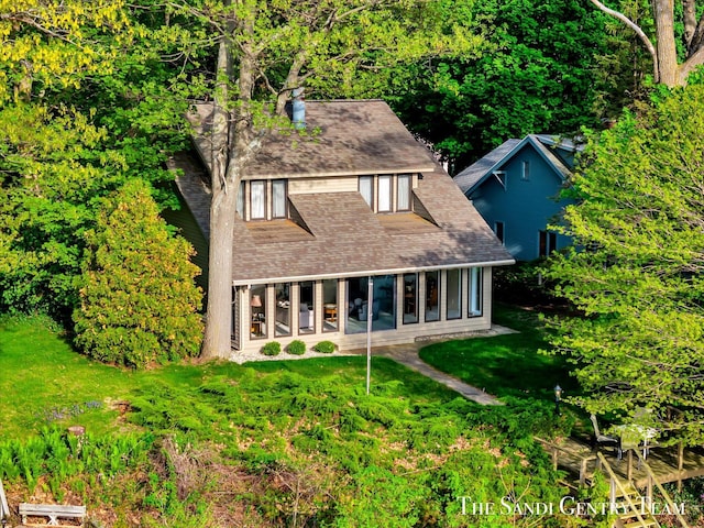 rear view of house featuring a yard, a sunroom, and roof with shingles