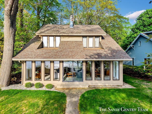 back of house featuring a chimney, a lawn, and a sunroom