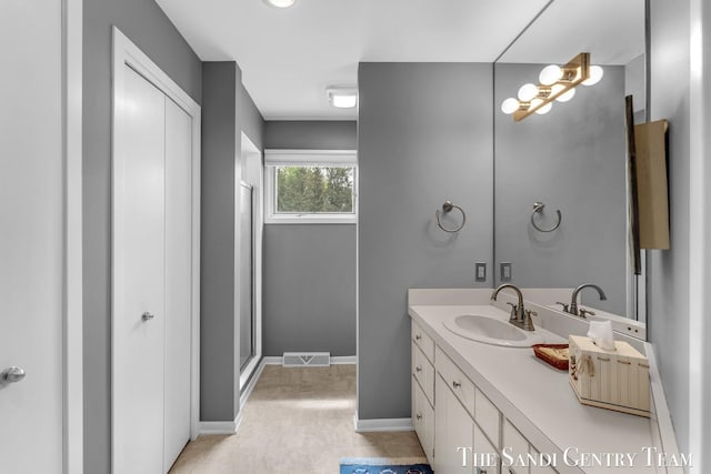 bathroom featuring vanity, a shower with door, and baseboards