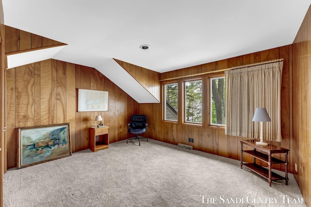 sitting room with wood walls, carpet, and vaulted ceiling