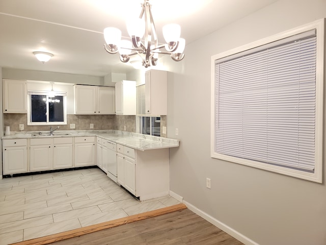 18453 Woodbine St, Detroit, MI 48219 - kitchen featuring a chandelier, tasteful backsplash, white cabinetry, baseboards, and a sink