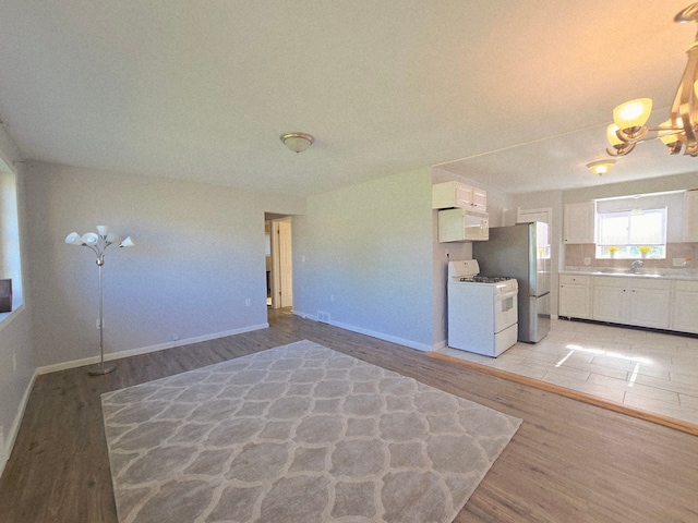 18453 Woodbine St, Detroit, MI 48219 - unfurnished living room featuring a sink, a chandelier, light wood-style flooring, and baseboards