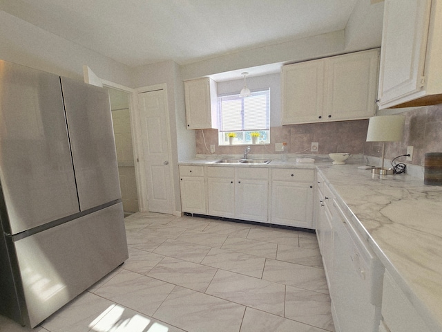 18453 Woodbine St, Detroit, MI 48219 - kitchen with a sink, backsplash, white cabinets, freestanding refrigerator, and light marble finish floors