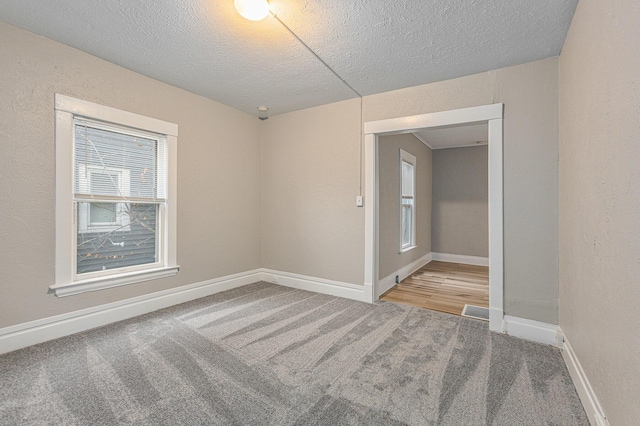 unfurnished room featuring carpet, a textured ceiling, and baseboards