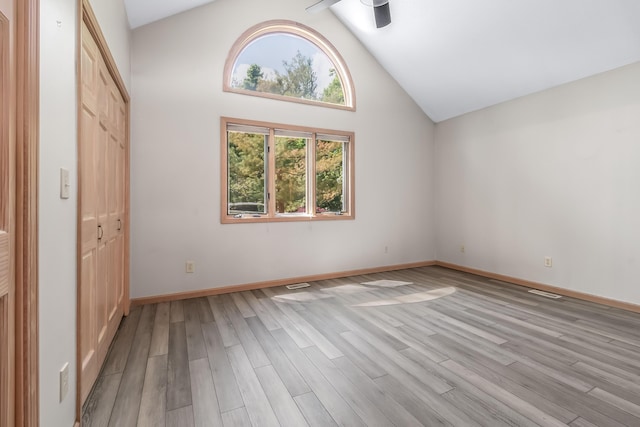 unfurnished bedroom with light wood-style flooring, a closet, baseboards, and high vaulted ceiling